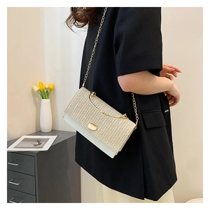 Détail du sac à bandoulière en paille et cuir blanc avec chaîne dorée et fermoir métallique