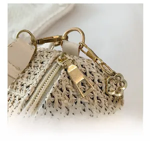 Detailed macro view of woven cream pillow bag with gold smooth zipper and floral chain