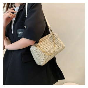 Détail d'un sac à main tissé avec chaîne à fleurs dorées sur un blazer noir élégant