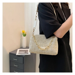 Détail du sac tressé beige avec chaîne de fleurs dorées et bandoulière en cuir