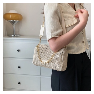 Détail du sac bandoulière en paille tressée avec chaîne dorée et sangle beige