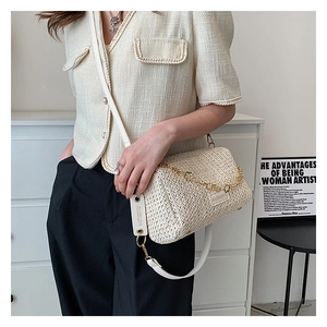 Texture tissée détaillée du sac bandoulière crème avec chaîne dorée et lanière blanche