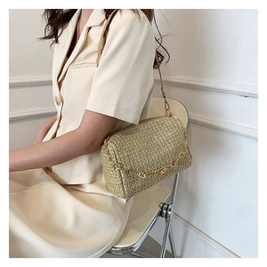 Détails de la texture du sac en paille tissée avec chaîne dorée et bandoulière
