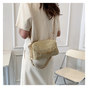 Detail of beige straw woven crossbody bag with gold zipper and leather shoulder strap