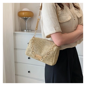 Détail du sac polochon en paille tressée beige avec étiquette et bandoulière chaîne