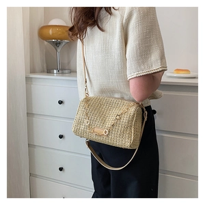 Détail d'un sac à bandoulière en paille tressée avec chaîne dorée et lanière en cuir