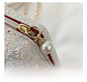 Detail of silver sequin shell bag featuring gold zipper and elegant faux pearl pendant