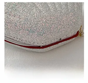 Macro detail of silver sequin bag with precise white stitching and red edge oil finish