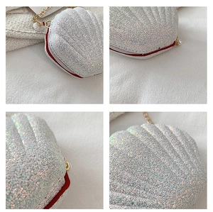Detail of silver sequin shell bag featuring red trim, gold chain, and a pearl zipper pull