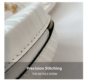 Détail macro des coutures de précision et du gaufrage vertical sur le sac rond en cuir blanc