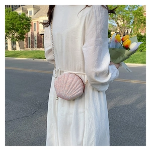 Detailed view of a pink sequin shell-shaped crossbody bag with a gold chain strap