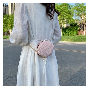 Detail of pink sequin shell bag with gold chain and pearl charm on shoulder