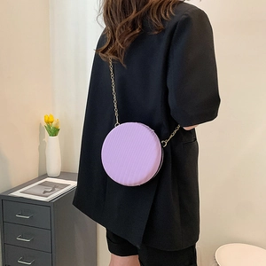 Détail d'un sac rond plissé violet doté d'une délicate bandoulière en chaîne dorée brillante