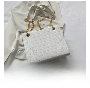 Dettaglio della borsa bianca motivo coccodrillo con catena d'oro su blazer bianco