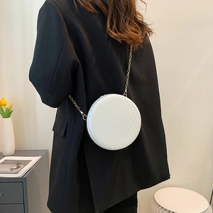 Sac rond blanc à chaîne avec texture de vagues porté par un mannequin en costume noir