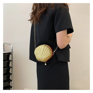 Detail of a mini shell bag with gold sequins, pearl charm, and fine chain strap on model