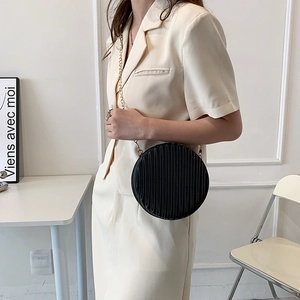 Détail du sac rond plissé noir avec une fine bandoulière en chaîne dorée élégante
