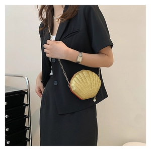 Close-up of golden sequin shell bag with metal chain strap and pearl pendant detail
