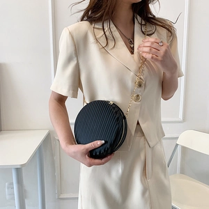 Détail du sac rond noir avec textures verticales et bandoulière en chaîne dorée