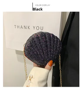Detail of black sequined shell-shaped evening bag with gold chain and pearl accent