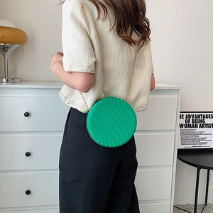 Détail du petit sac rond plissé vert avec bandoulière chaîne dorée porté par un mannequin