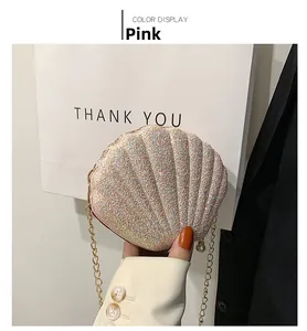 Detailed view of pink sequined shell clutch featuring gold chain and pearl accent