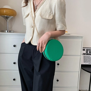 Détail du petit sac rond vert à bandoulière avec texture plissée et chaîne dorée chic