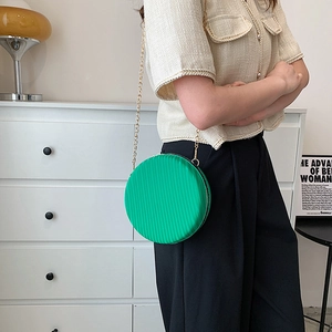 Détail d'un sac rond vert émeraude avec texture plissée et fine bandoulière dorée