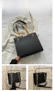 Dettaglio della borsa tote nera a trama coccodrillo con catena d'oro e design rigido