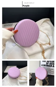Détail d'un sac rond violet à texture ondulée avec une fine bandoulière en chaîne dorée