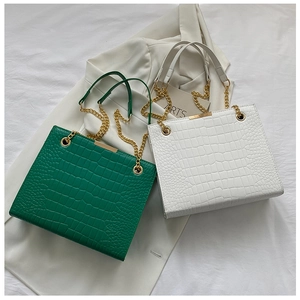 Close-up of crocodile pattern tote bag in green and white with gold chain details