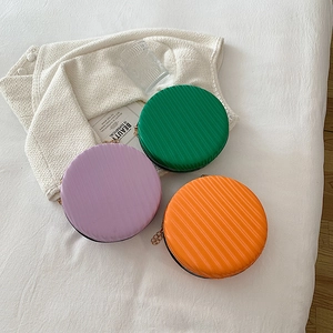 Détail de mini sacs ronds rigides colorés en vert, violet et orange avec bandoulière chaîne