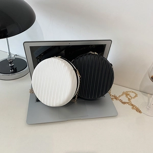 Détail de sacs bandoulière ronds plissés en noir et blanc avec chaînes dorées