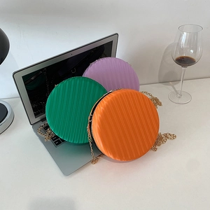 Détail des sacs ronds rayés colorés en vert, violet et orange avec chaîne dorée