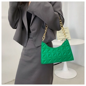 Detail of green triangle quilted shoulder bag with chunky gold chain strap on model