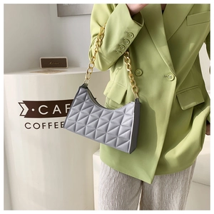 Close-up of grey quilted baguette bag featuring a chunky gold chain strap for women
