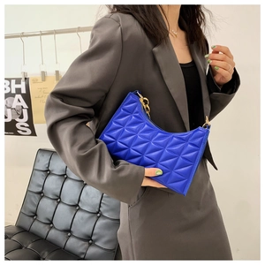 Detail of royal blue quilted shoulder bag with gold chain and chic crescent shape
