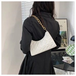 Close-up of white quilted faux leather underarm bag with thick gold chain shoulder strap