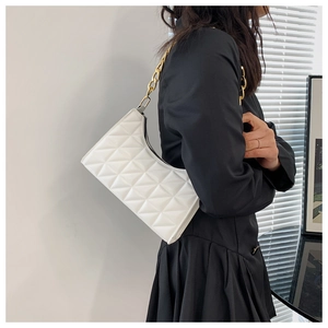 Detail of white quilted baguette bag with geometric patterns and a chunky gold chain strap