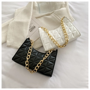 Close-up of quilted geometric pattern and luxury gold chain on black and white shoulder bags