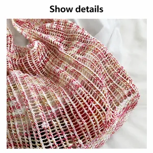 Gros plan sur la maille ajourée et le fil rose et jaune doux du sac cabas tricoté
