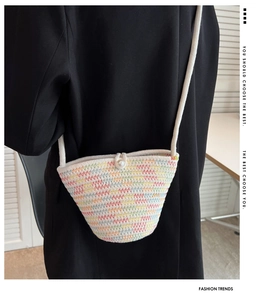 Detail of colorful woven bucket bag with rainbow patterns and faux pearl closure