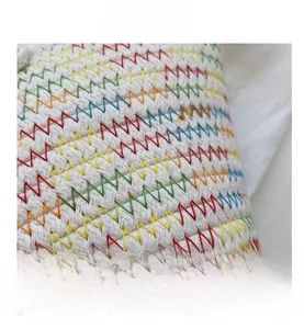 Macro shot of white woven bucket bag featuring multicolor wave-shaped embroidery details