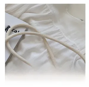 Detail showing the thick cream woven rope shoulder strap and textured cotton fabric