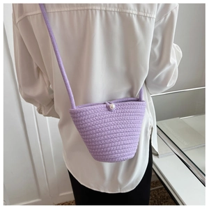 Detail of lavender woven bucket bag featuring pearl clasp and adjustable strap