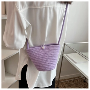 Detail of purple hand-woven bucket bag with a white pearl clasp and knitted texture