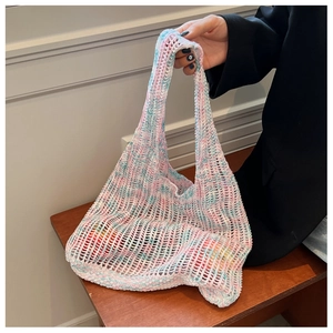 Detail einer handgehäkelten Mesh-Tasche in Pastellrosa und Blau mit geflochtenen Griffen