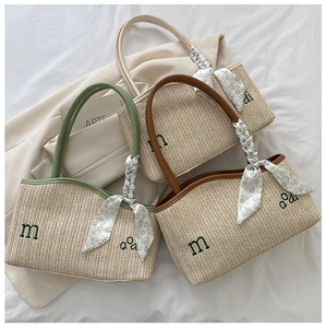 Close-up of three woven straw tote bags in green brown and beige with silk scarves