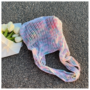 Nahaufnahme der pastellfarbenen Häkel-Schultertasche mit Lochmuster auf dem Asphalt