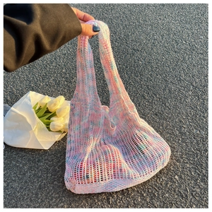Detail der gehäkelten Tragetasche in Rosa und Blau mit weißen Tulpen auf Asphaltweg